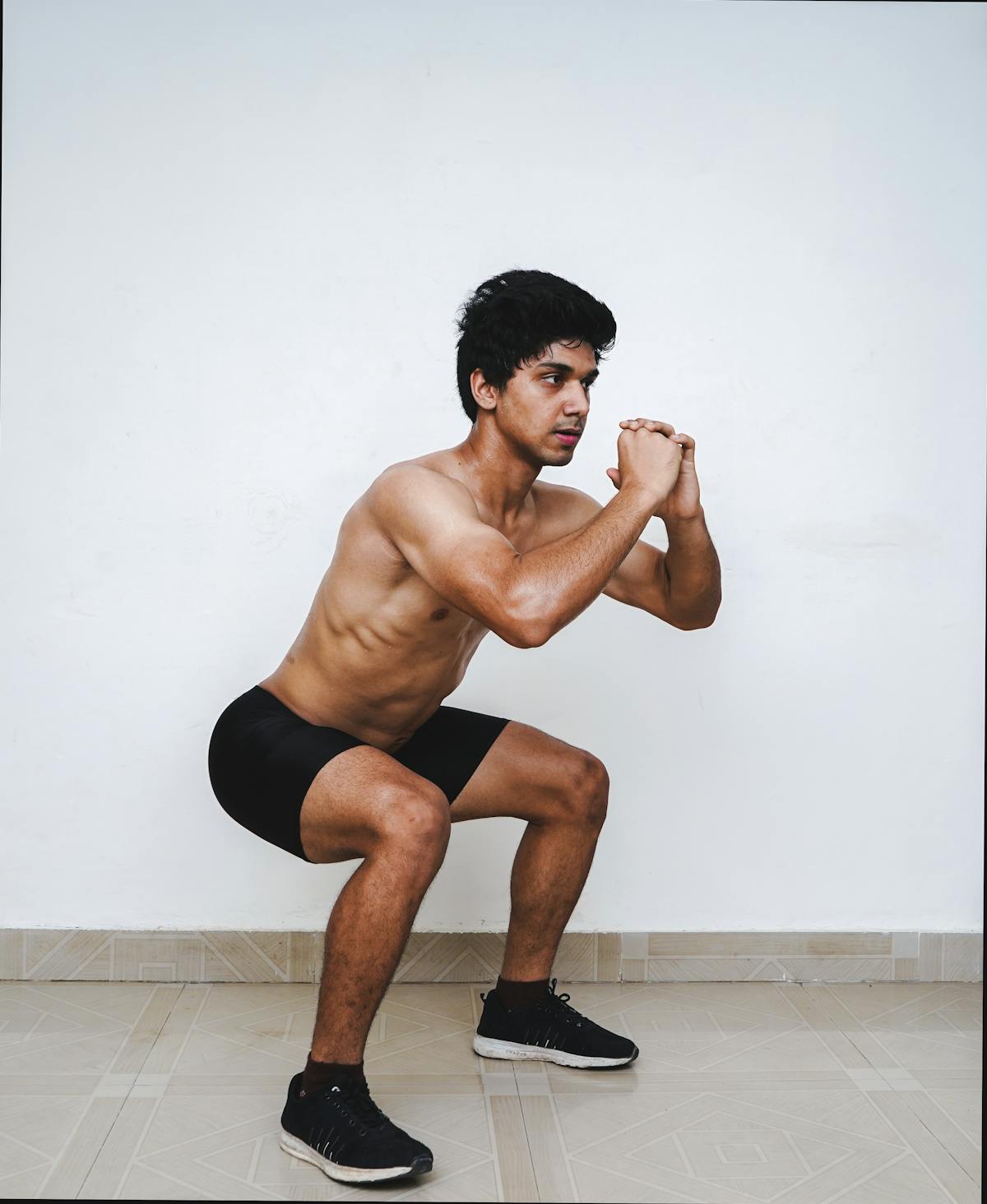 Young athlete performing a bodyweight squat with proper hip-dominant form